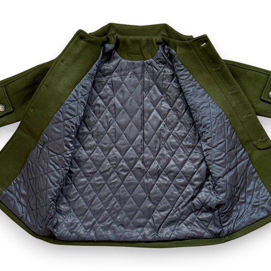 Olive boiled wool children’s pea coat with raglan sleeves, flap pockets, sleeve tabs and quilted lining.