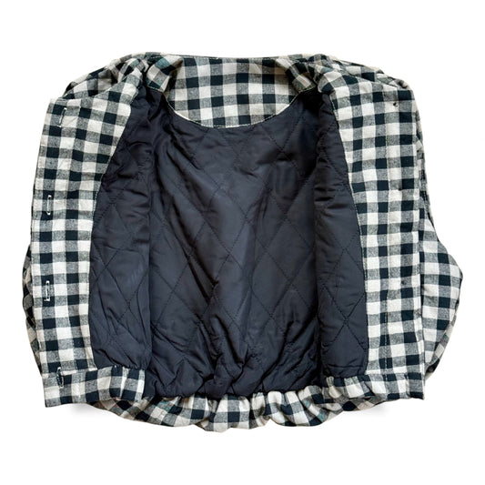 Black-and-cream gingham quilted children’s gilet with petal-shaped pockets and popper fastening.