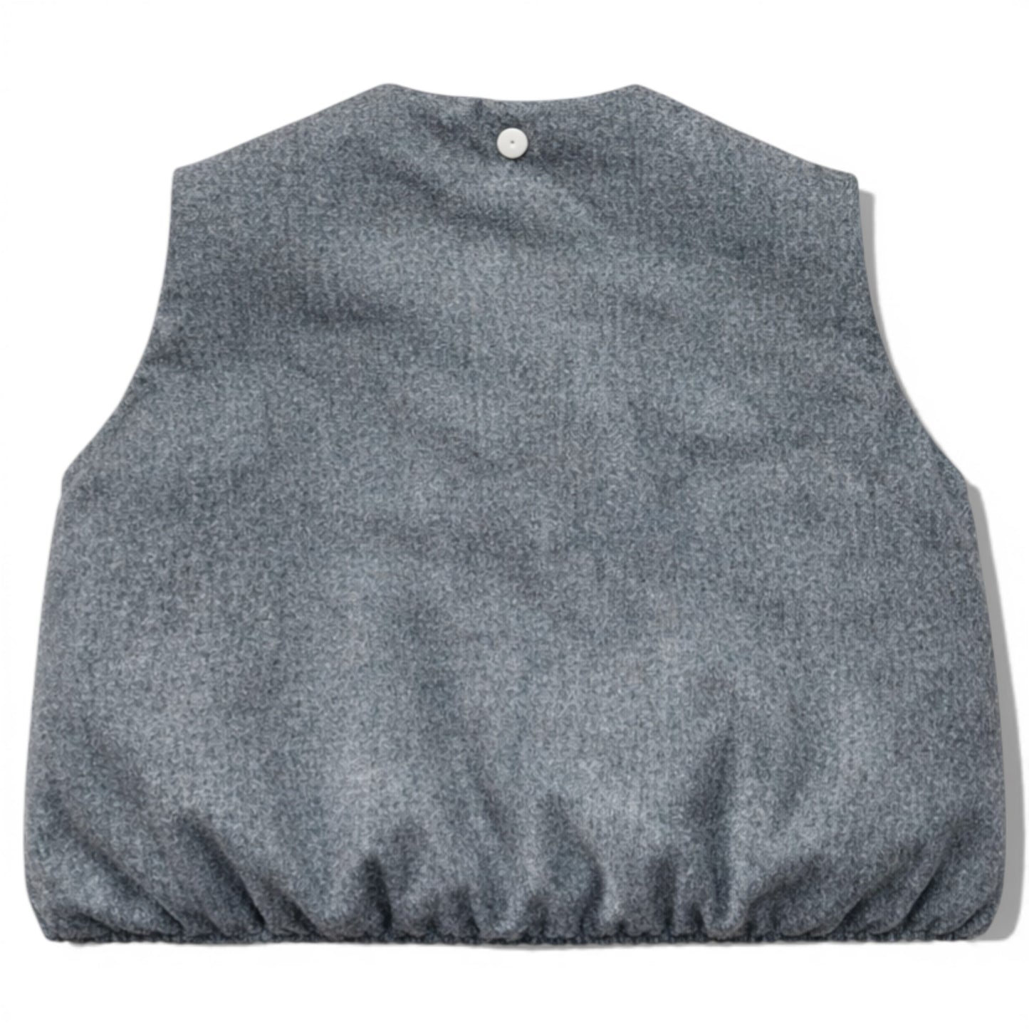 Kids grey wool sleeveless gilet with quilted interior, elastic hem and hidden popper placket. Grey wool children’s gilet cut on the bias for a swing silhouette