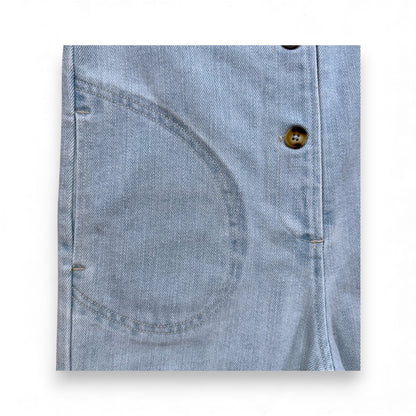Light blue denim children’s romper with scoop neckline, circular front pockets and full front button closure