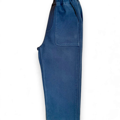 Side view of close-fit blue Nour Pants with deep front patch pocket and straight leg