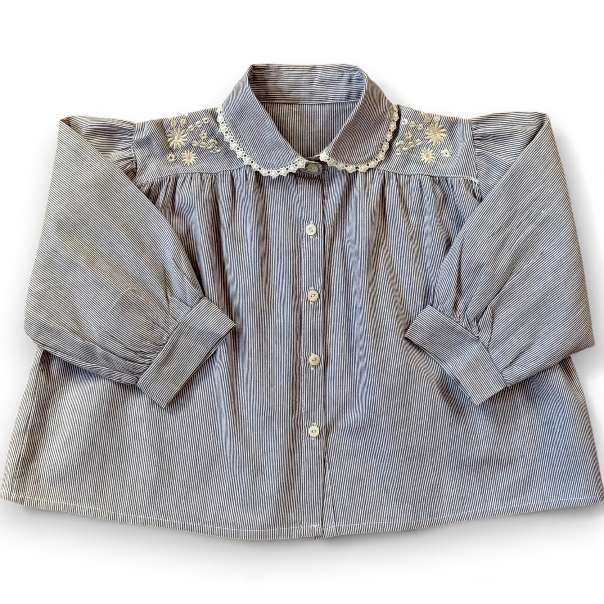 Children’s pinstripe A-line blouse with lace-trimmed Peter Pan collar, embroidery on shoulders and pleated front.