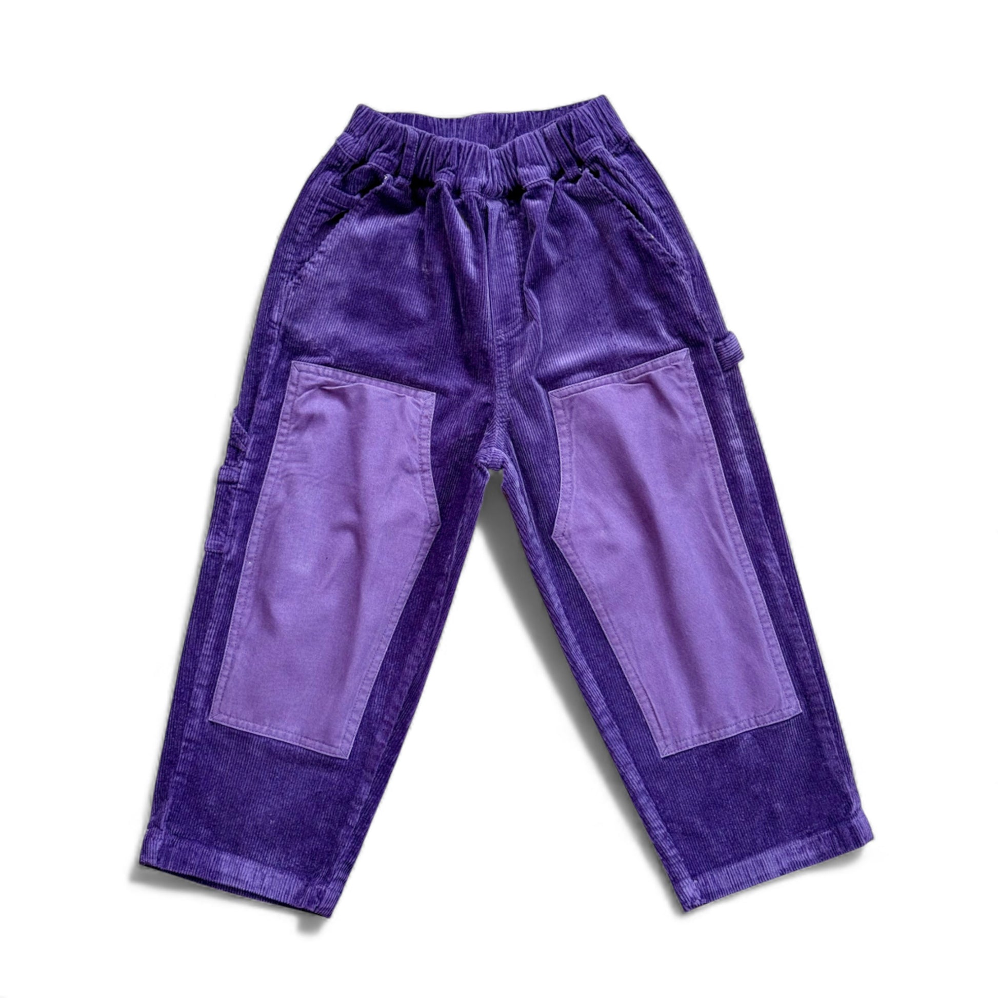 Purple corduroy children’s trousers with contrast knee patches, slant pockets and straight leg — front view.