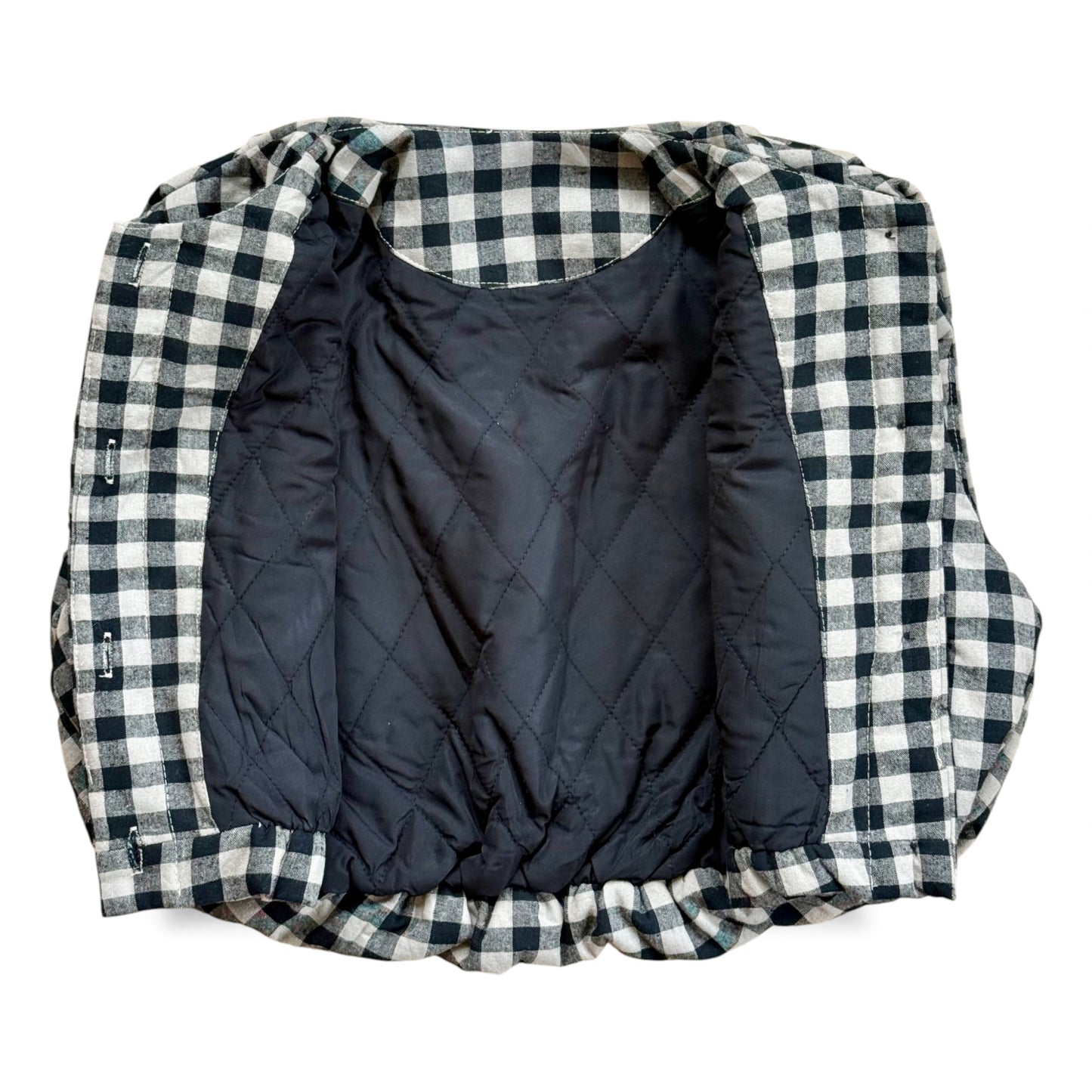Black-and-cream gingham quilted children’s gilet with petal-shaped pockets and popper fastening.