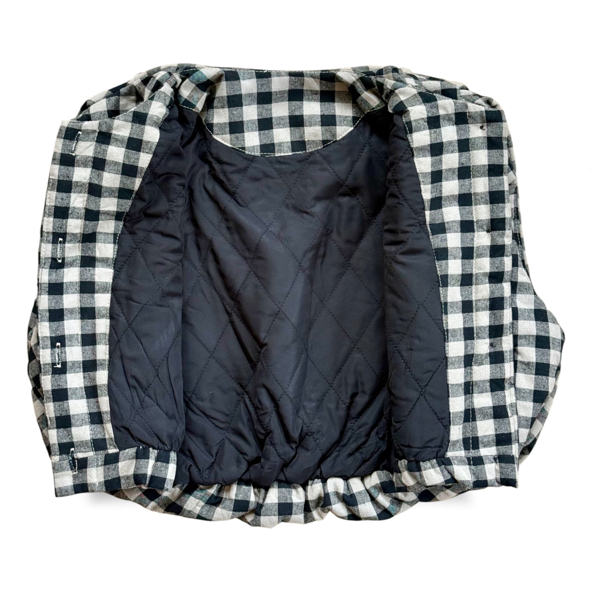 Black-and-cream gingham quilted children’s gilet with petal-shaped pockets and popper fastening.