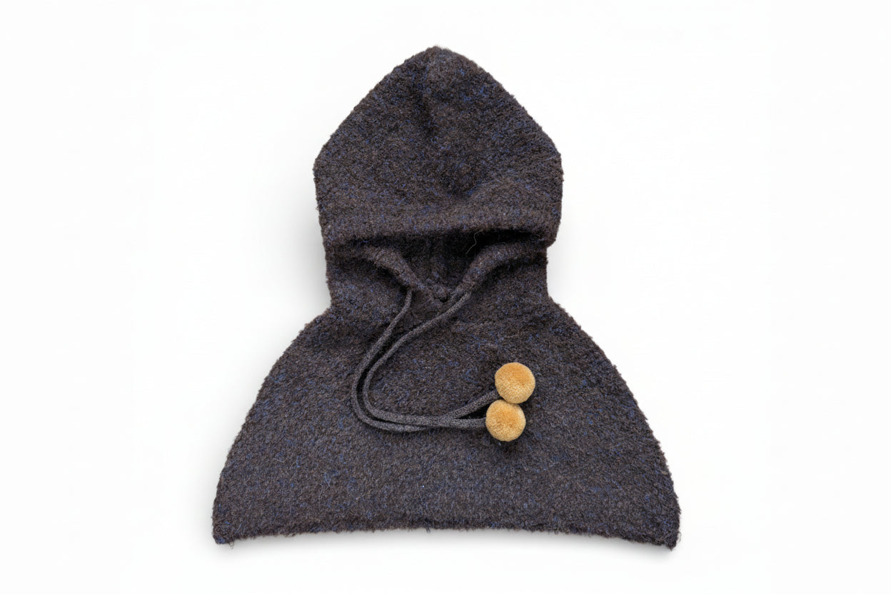 Children’s wool hooded shoulder cape in dark brown with drawstring and pom-pom ties, designed to sit on the shoulders and be worn under a coat.