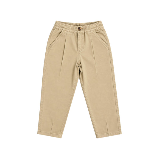 Front view of the Nyima sand cotton trousers with an elasticated waistband, front pleats, angled pockets and tapered legs with darted hems.