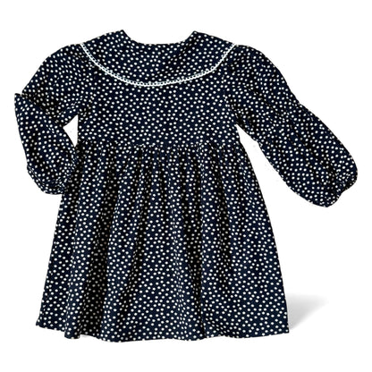 Navy brushed-cotton children’s dress with white micro-floral print, layered petal collar with contrast trim, long balloon sleeves with mid-arm and cuff elastic, empire line and gathered skirt — back view.
