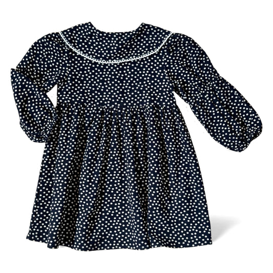Navy brushed-cotton children’s dress with white micro-floral print, layered petal collar with contrast trim, long balloon sleeves with mid-arm and cuff elastic, empire line and gathered skirt — back view.