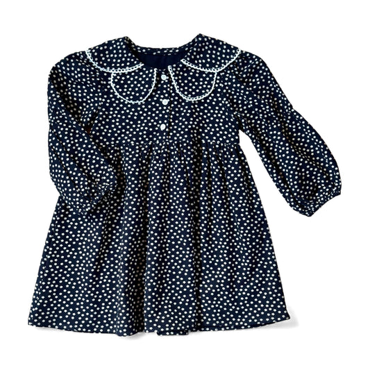 Navy brushed-cotton children’s dress with white micro-floral print, layered petal collar with contrast trim, long balloon sleeves with mid-arm and cuff elastic, empire line and gathered skirt — front view.