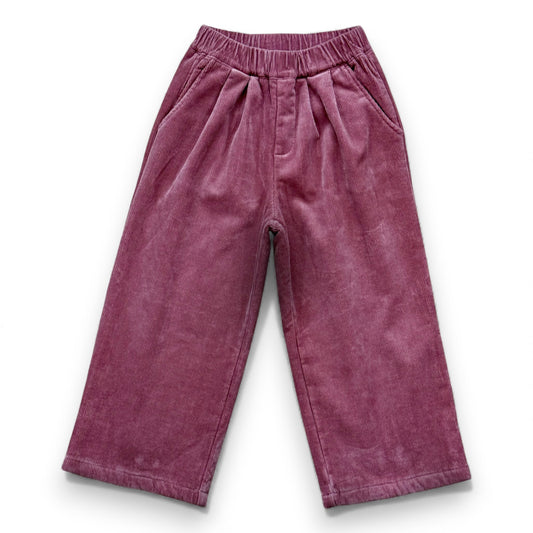 Front view of pastel pink wide-leg corduroy children’s trousers with slant pockets, light pleating and elastic waistband by That’s Not Fair London